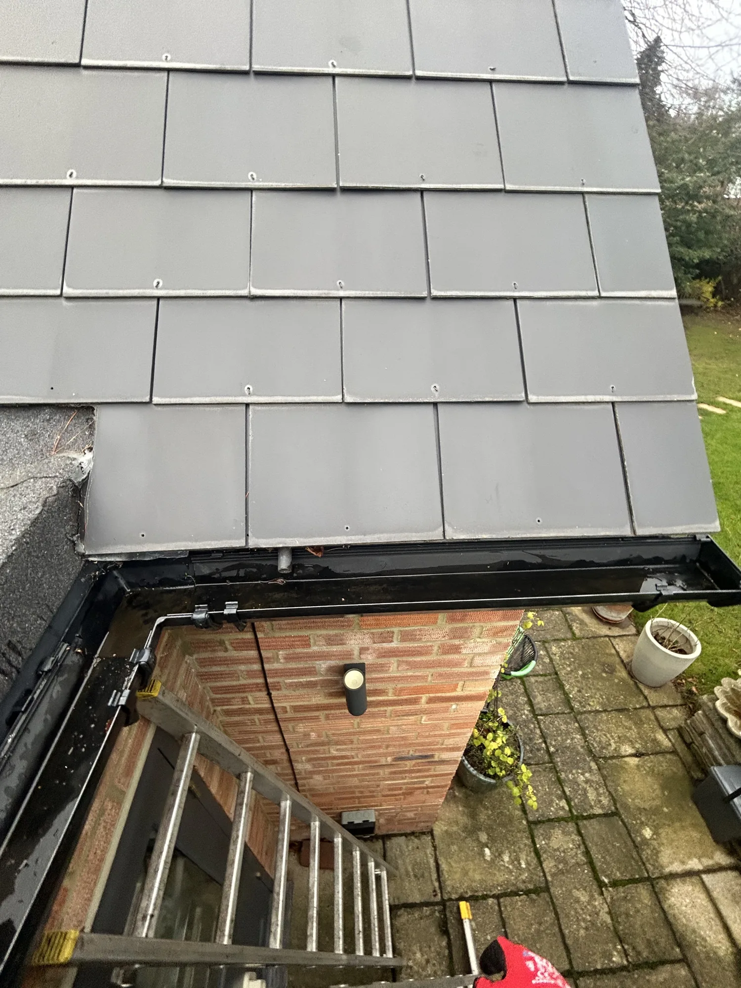 Black box gutter along a grey tiled extension with ladder access in Rickmansworth