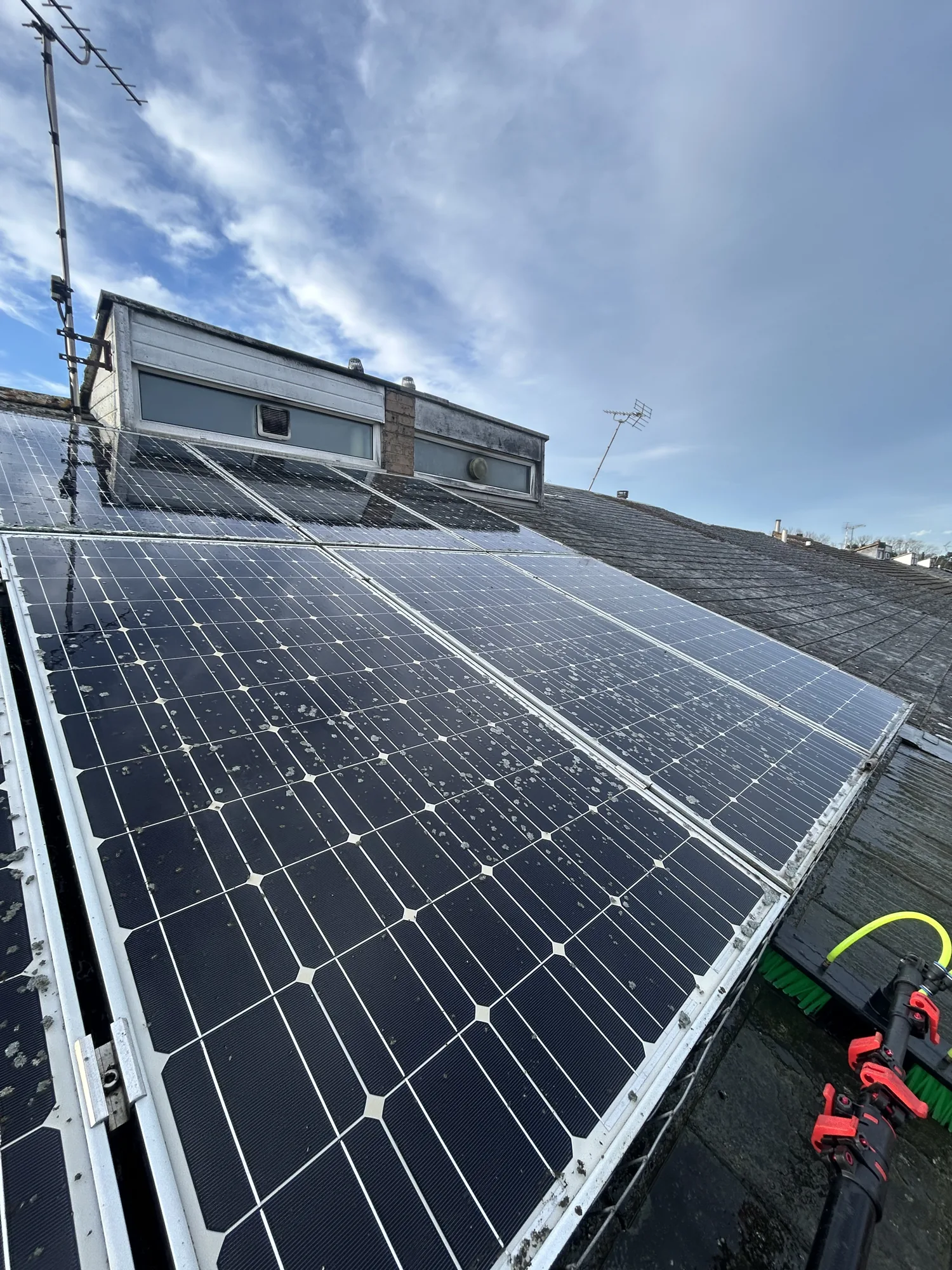 Soiled solar panels with cleaning brush before a water fed pole clean